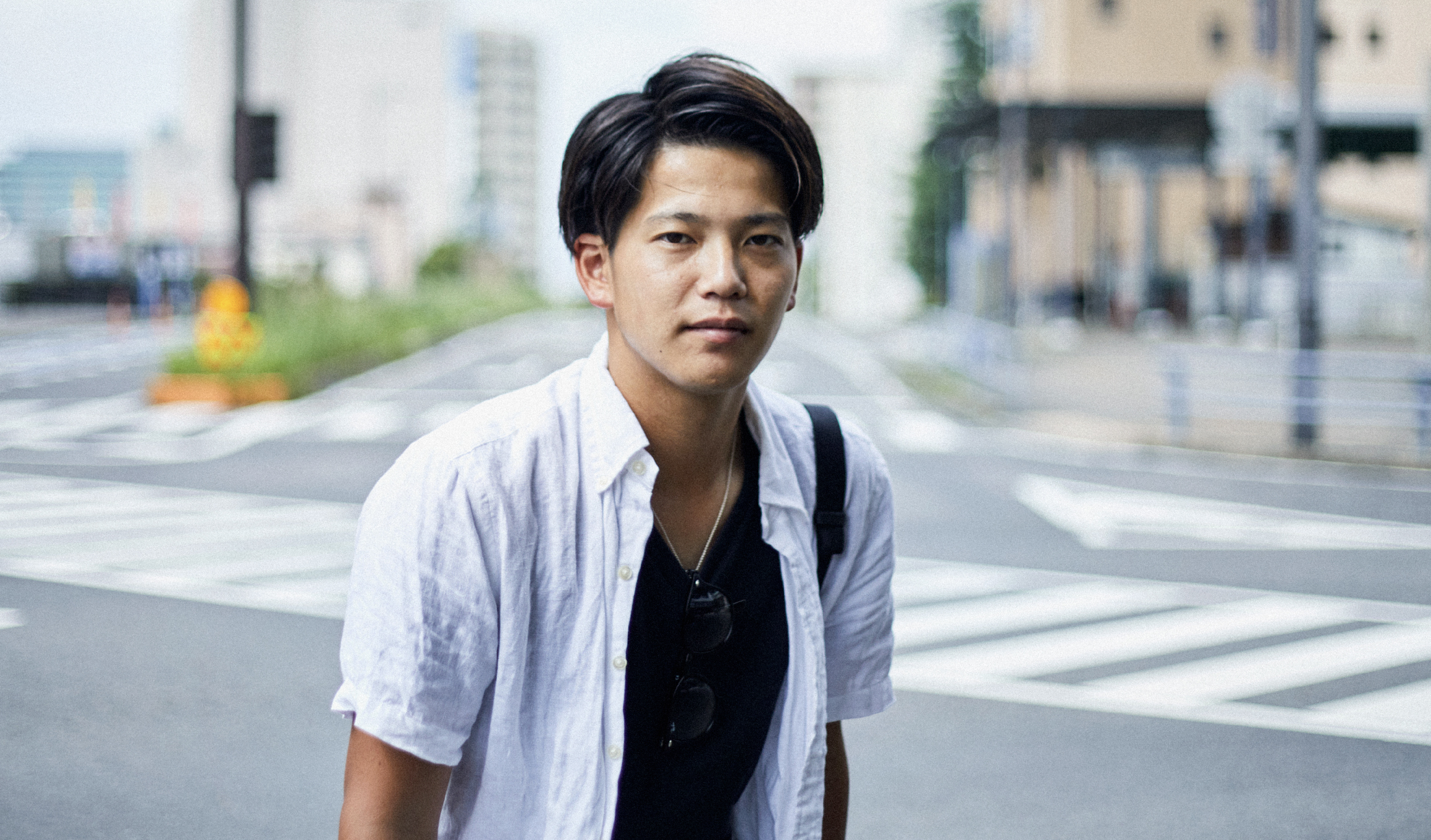 街で青年がカメラ目線でこちらを見ている