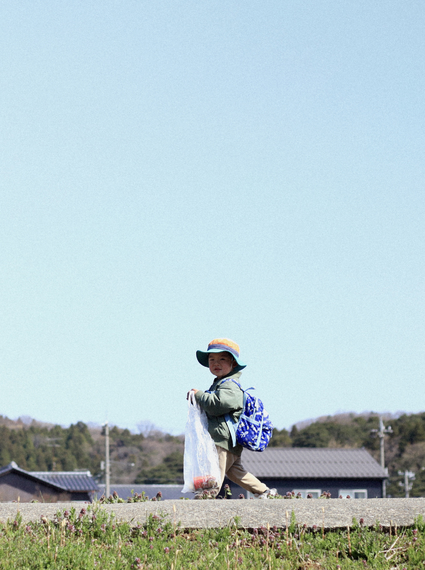 子供が手提げ袋を持ってこちらを見ている